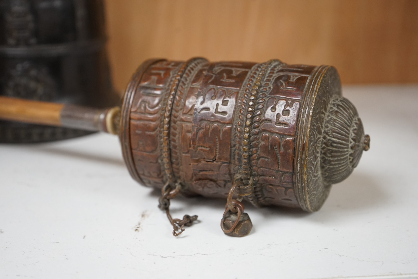 A late 19th/early 20th century Tibetan prayer wheel, with silver mounted bamboo handle, and a Southeast Asian bronze bell, largest 28cm wide. Condition - fair